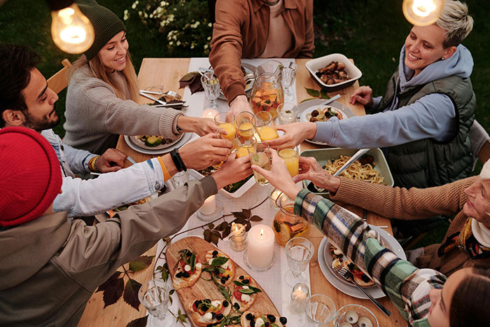 Family enjoying Thanksgiving dinner, toasting with drinks around a festive table.