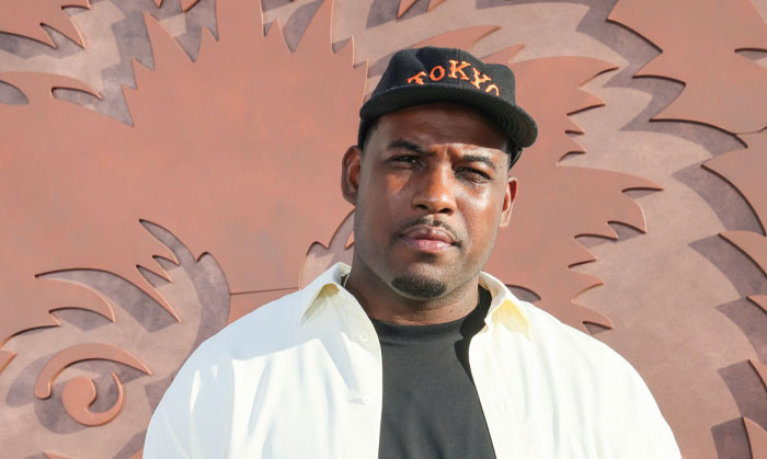 Lionel Boyce in a white shirt and black hat with "Tokyo" posing against a decorative wall, related to "The Bear" returning stars.