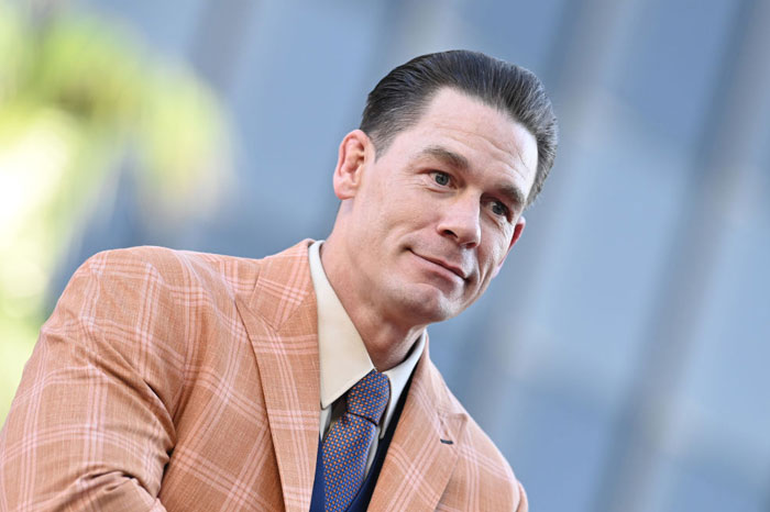 John Cena in a plaid suit and tie, featured in The Bear's exciting guest appearances for Season 3.