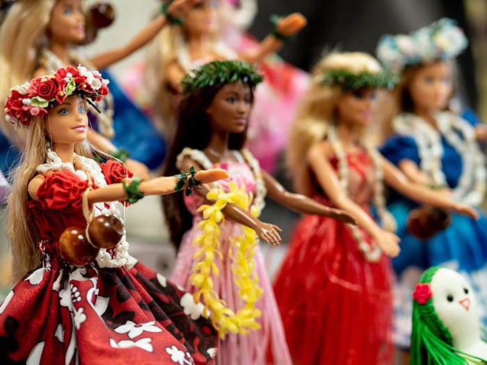 Hawaiian-themed dolls in colorful dresses, representing things bought as adults denied in childhood.