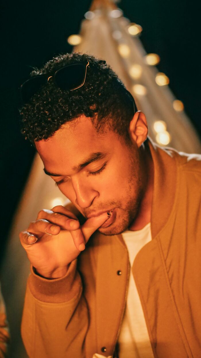 Man in a casual setting wearing a jacket, biting his thumb, representing behaviors people secretly judge others for.