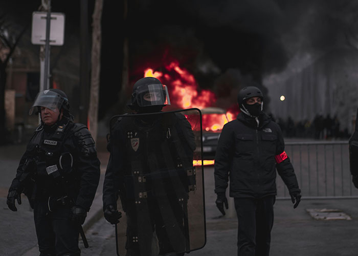 Riot police in gear with a burning car in the background, symbolizing terrible outcomes of desired things.
