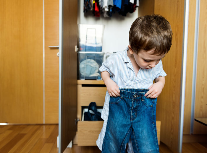 Child in room holding jeans, part of a discussion on prioritizing Bible study over sports activities in families. Child in room holding jeans, part of a discussion on prioritizing Bible study over sports activities in families.