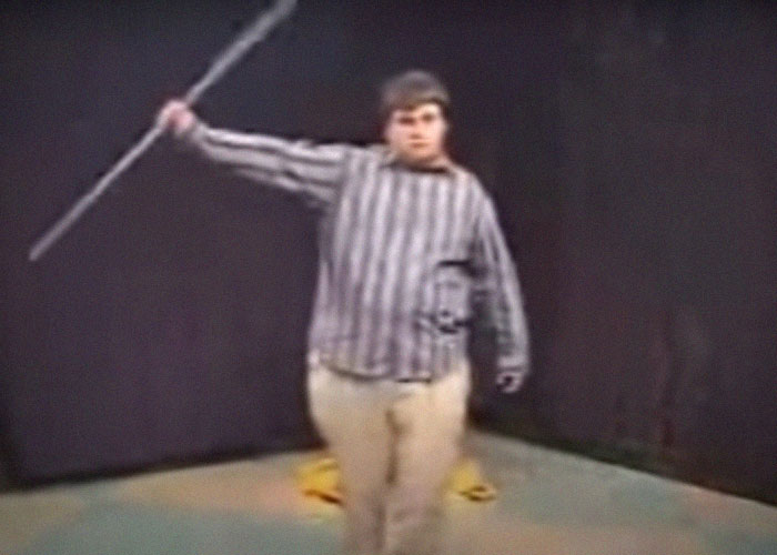 Person in striped shirt holding a staff, showcasing intriguing skill in a video setting.