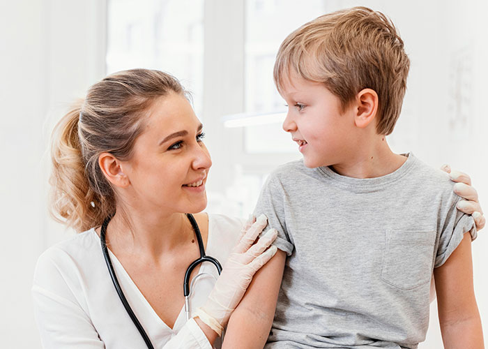 Doctor smiling at a boy, both in a clinic setting, capturing an intriguing healthcare moment.