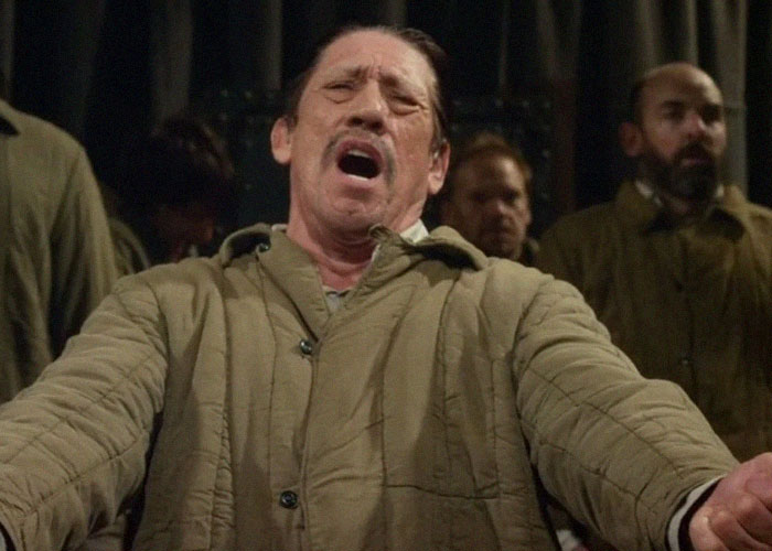 A man performing passionately in a dramatic scene, wearing a beige coat, conveying intriguing facts.