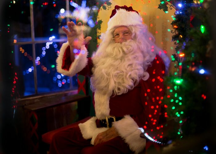 Santa Claus at a work Christmas party, surrounded by colorful lights and holiday decor.