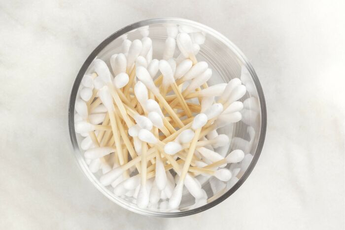 Bowl of cotton swabs on a marble surface, illustrating hygiene hacks.