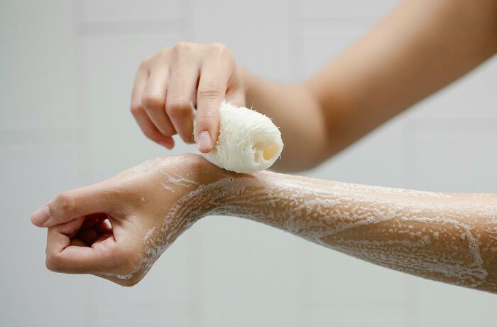 Applying a pumice stone to exfoliate the arm, illustrating hygiene hacks.