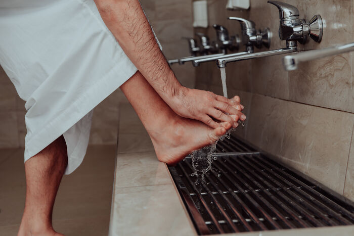 Person washing feet under a faucet, illustrating hygiene hacks. 