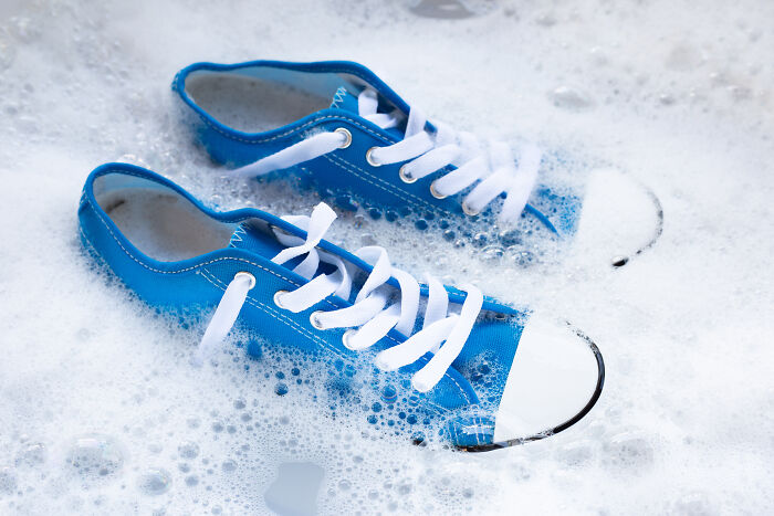 Blue sneakers soaking in soapy water, illustrating hygiene hacks. 