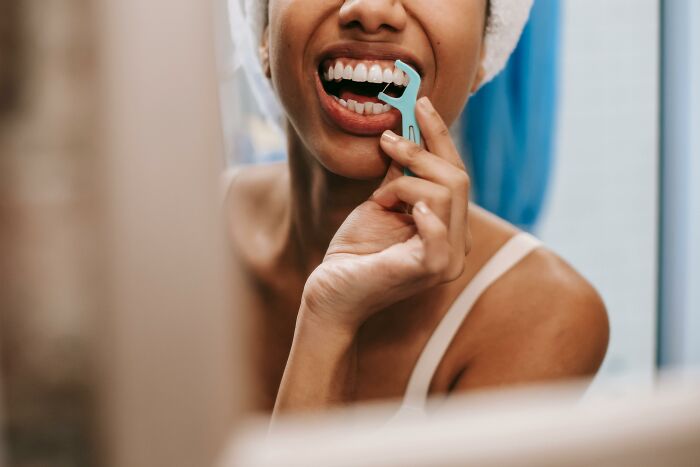 A person using a dental flosser, illustrating hygiene hacks.