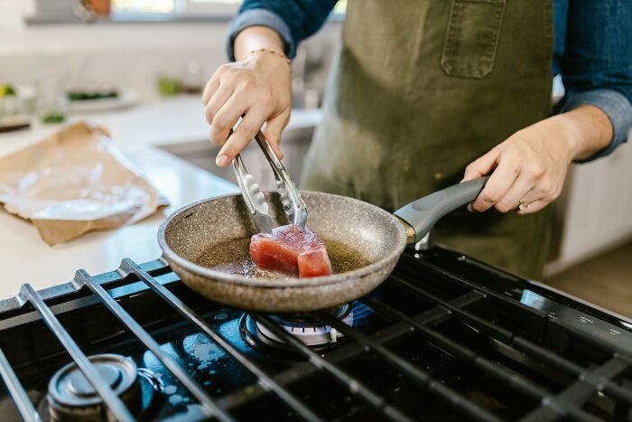 Person cooking meat in a pan on the stove, sparking drama with vegan neighbors. Person cooking meat in a pan on the stove, sparking drama with vegan neighbors.