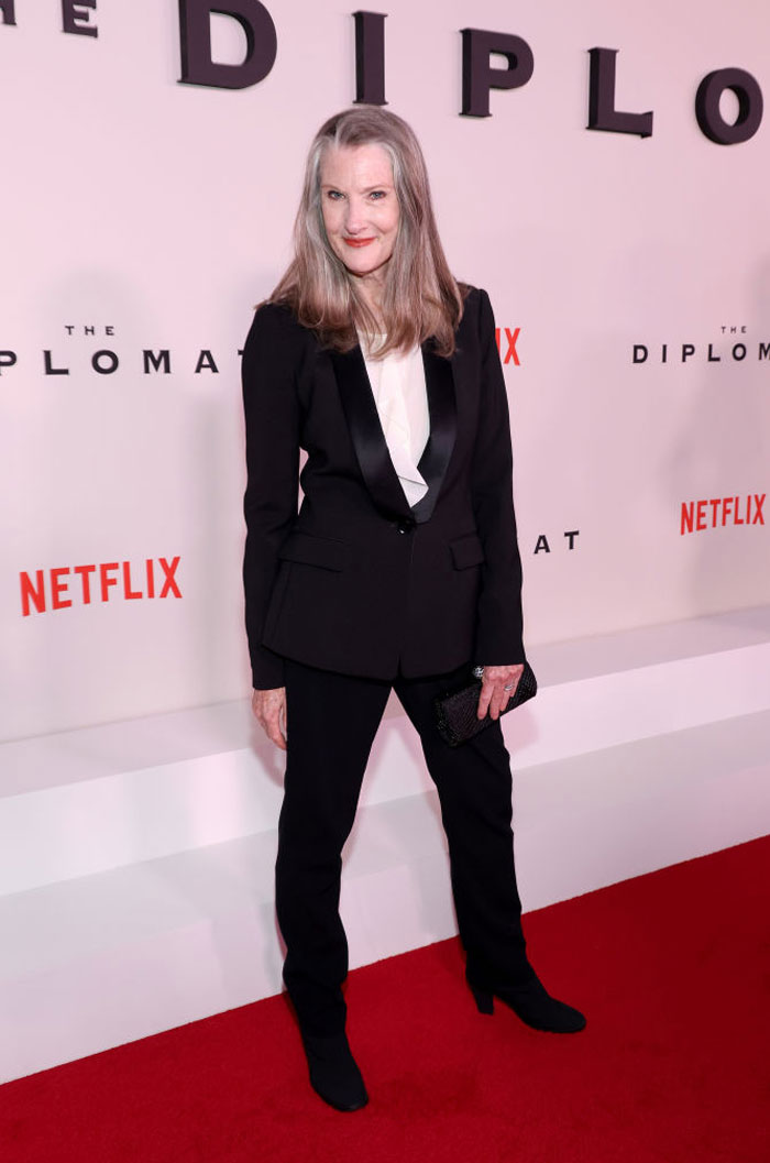 "Virgin River cast member in a black suit at a Netflix premiere, posing on the red carpet."