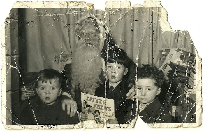 Vintage photo of a creepy Santa with three children holding a book.