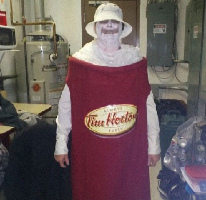 Person in humorous Tim Hortons costume in a utility room, embodying bizarre social media trends.