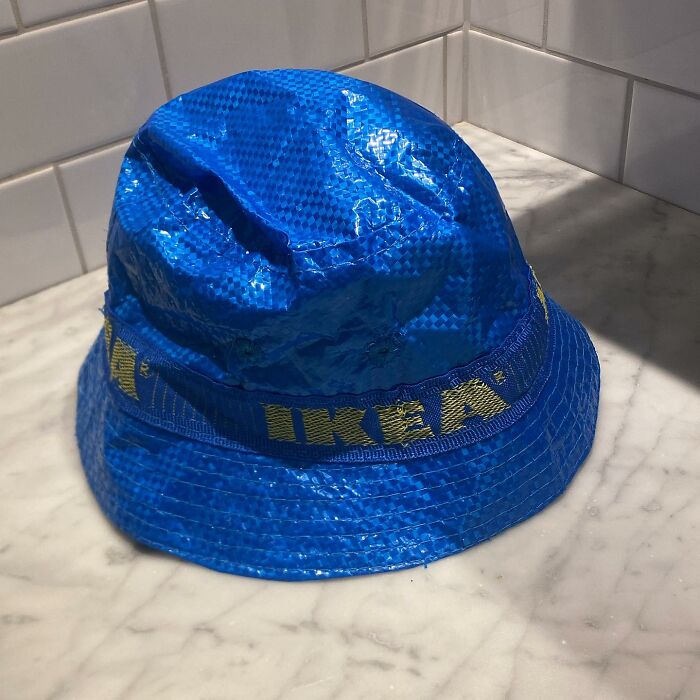 Blue IKEA bucket hat on marble countertop, humorously crafted from iconic shopping bag material.