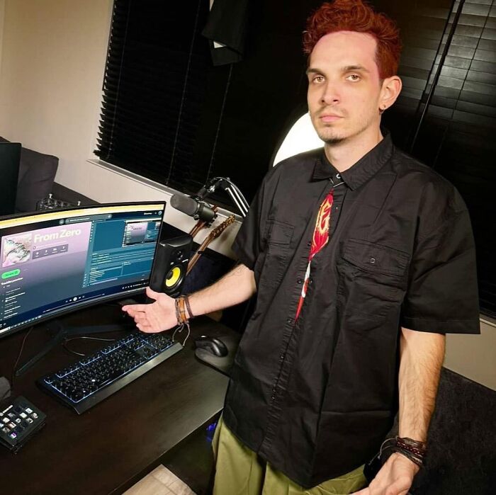 Man stands by computer setup with funny expression, illustrating bizarre social media post.