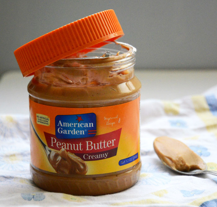 Open jar of creamy peanut butter with a spoon beside it, illustrating a discussion about peanut allergies.