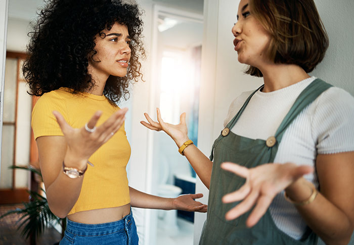 Two women having a heated discussion at home, expressing frustration and disagreement.