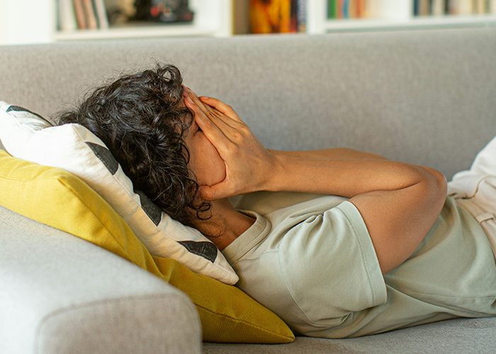 Person lying on a couch, covering face in frustration, illustrating relationship stress from toxic family boundaries. Person lying on a couch, covering face in frustration, illustrating relationship stress from toxic family boundaries.