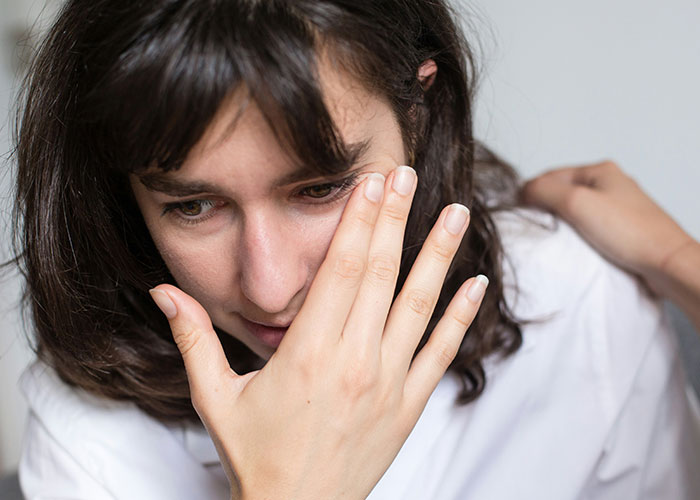 A woman looks distressed as another person touches her shoulder, symbolizing toxic family dynamics and relationship tension. A woman looks distressed as another person touches her shoulder, symbolizing toxic family dynamics and relationship tension.