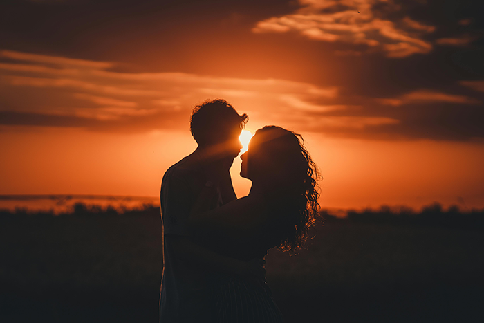 Couple silhouetted at sunset, representing relationship turmoil and secrets.