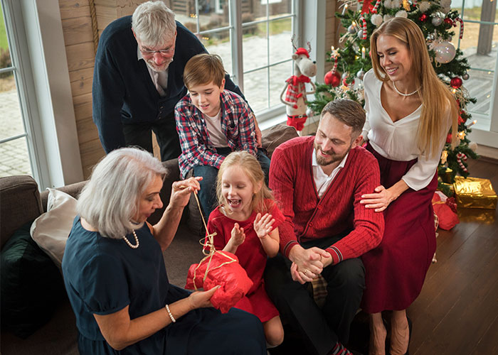 Family gathering around a Christmas tree, exchanging gifts and enjoying holiday moments together.