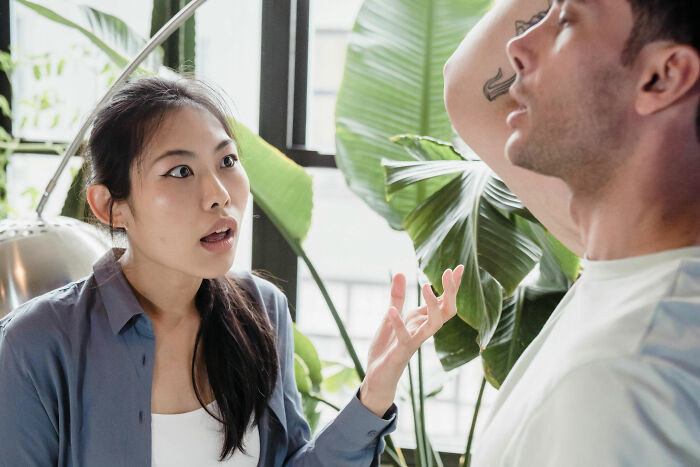 Woman expressing frustration to her partner in a room with plants, discussing his close relationship with his mother.