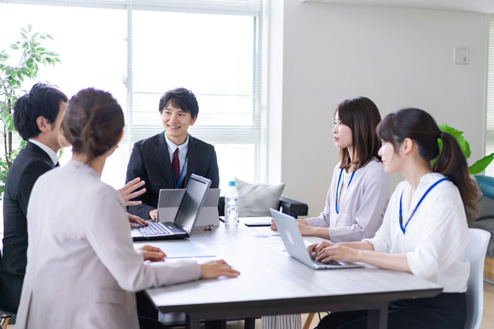 Japanese office workers in a meeting, with laptops and documents on the table. Japanese office workers in a meeting, with laptops and documents on the table.