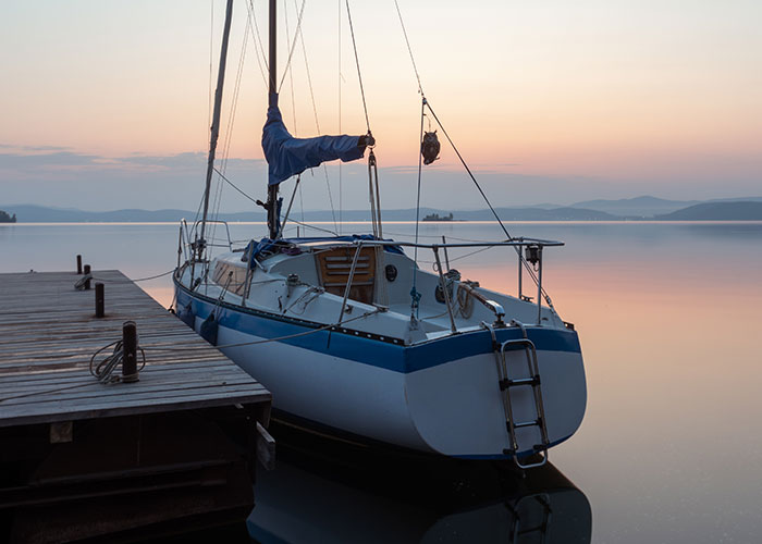 Sailboat docked at sunset, calm sea in background, highlighting sightings at sea.