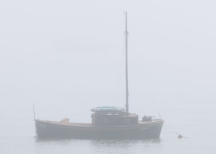 A lone boat floats in the misty sea, creating a mysterious sighting at sea.