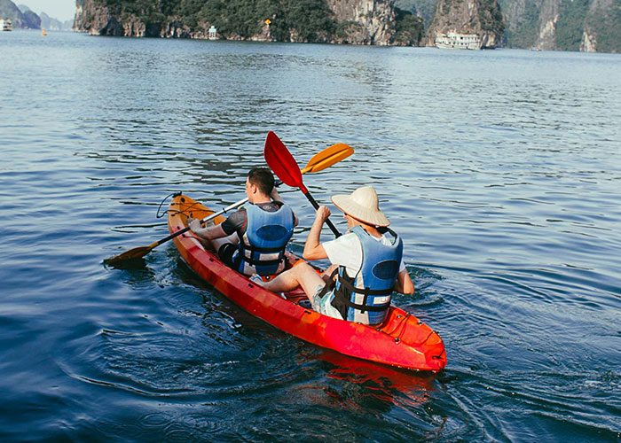 Two people kayaking at sea with scenic views, emphasizing the vast and open water.