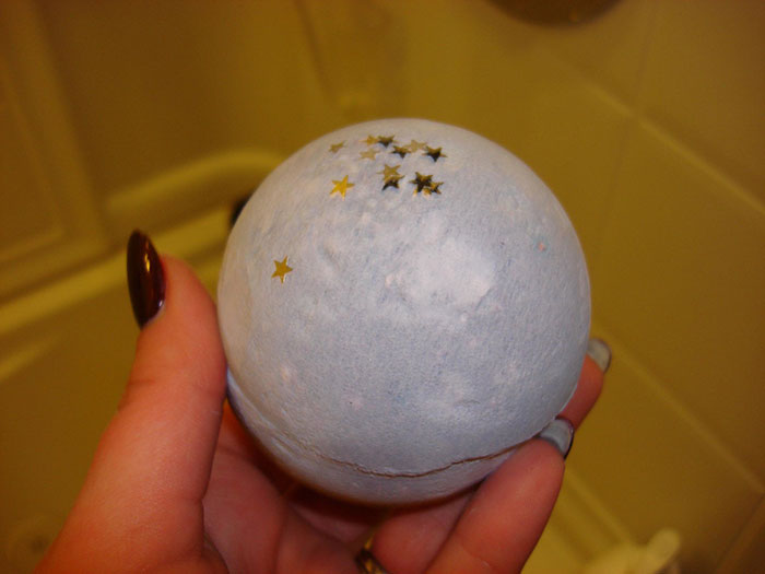 Hand holding a bath b**b with star decorations, representing a Christmas present that ruined the holiday spirit.