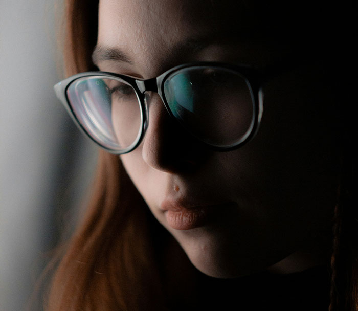 "Close-up of a person wearing glasses, reflecting on disappointing Christmas presents."