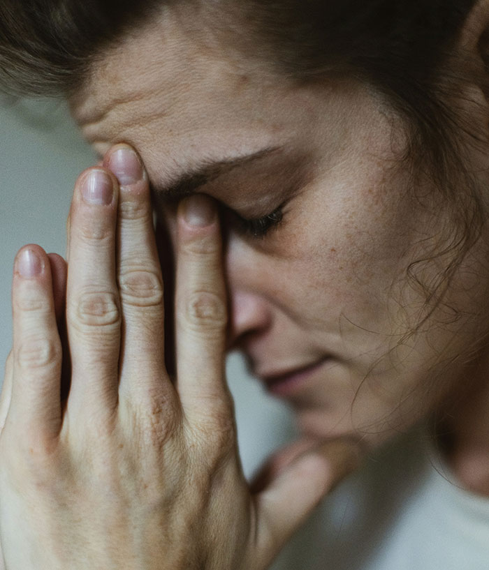 Woman covering face with hands, reflecting on ruined holiday spirit due to Christmas gift disappointment.