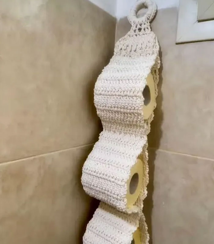 Crocheted toilet paper holder in a bathroom corner, an unusual Christmas present that might ruin holiday spirit.