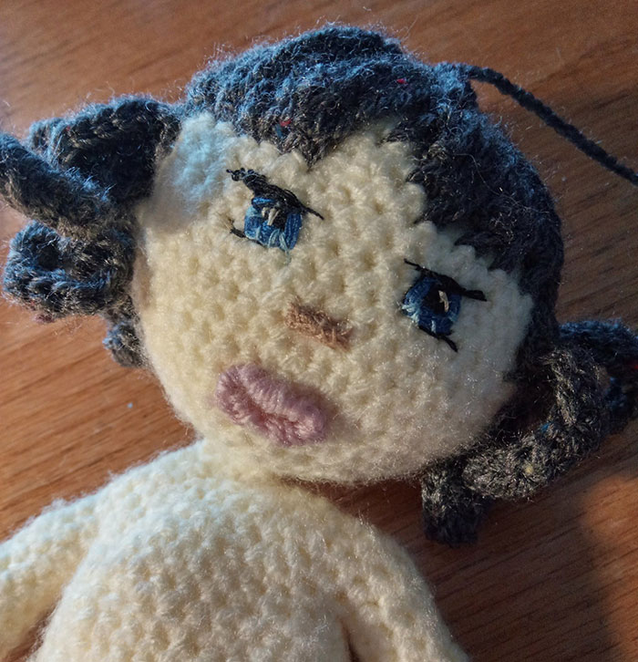 Handmade crochet doll with dark hair and blue eyes, representing a disappointing Christmas present.