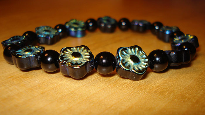 Black and green floral bracelet on a wooden surface, representing a Christmas present that ruined the holiday spirit.