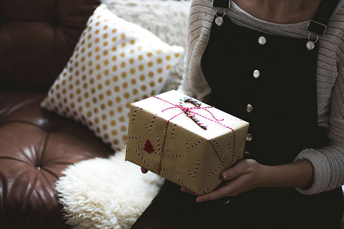 Person holding a wrapped Christmas gift, symbolizing holiday presents.