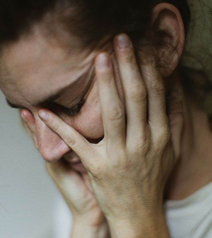 A woman with her face in her hands appears stressed, reflecting a maternity employee's challenging experiences.