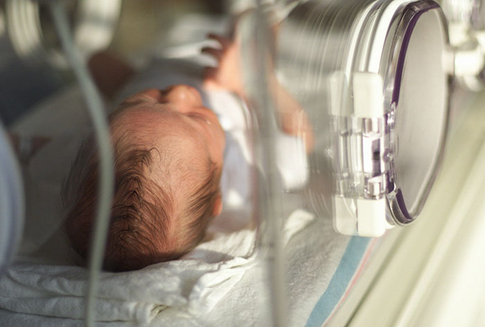 Newborn baby in a hospital incubator, illustrating stories from maternity employees.