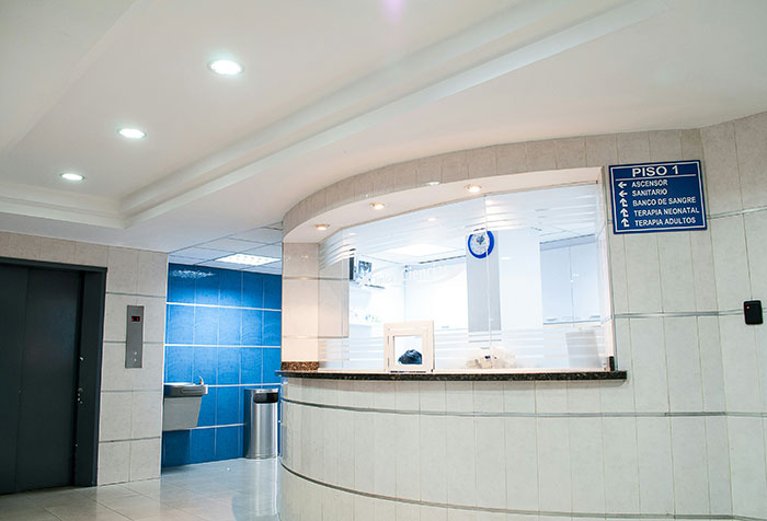 Hospital maternity reception area with blue signage and bright lighting.