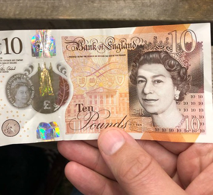 Hands holding a £10 note, relating to the worst luck with Secret Santa.