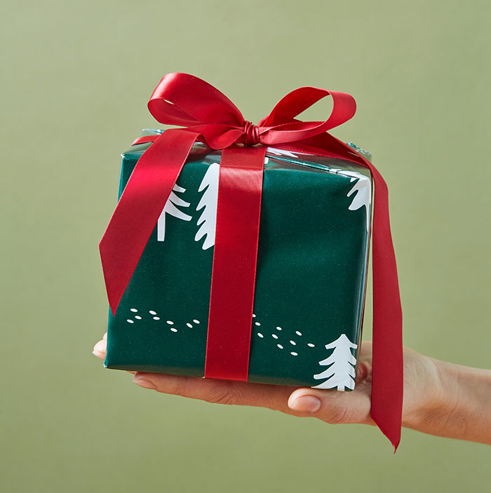 Gift wrapped in green paper with red ribbon, symbolizing Secret Santa exchange.