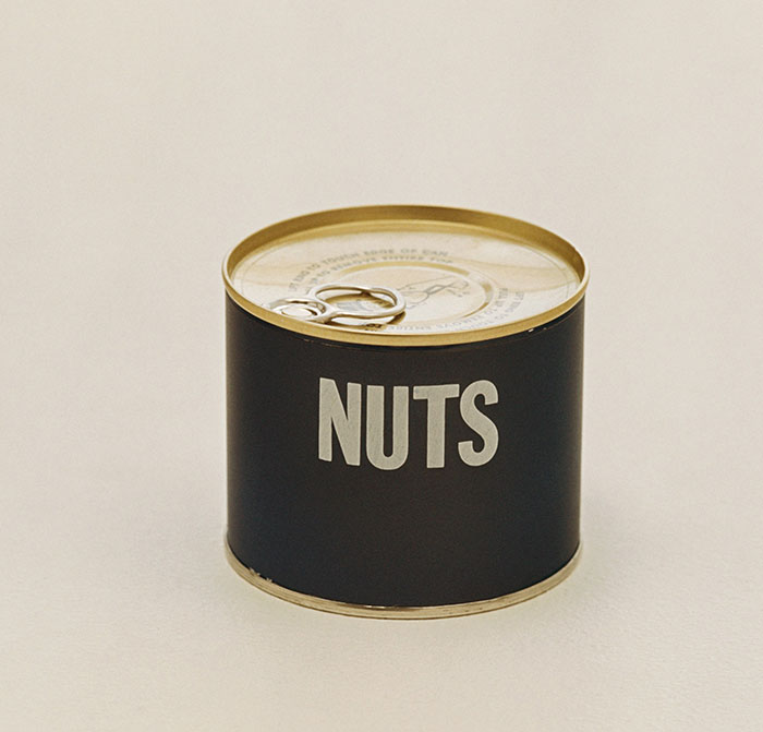 Can labeled "NUTS" on a neutral background, related to Secret Santa gift exchange.