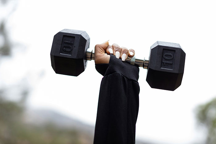 Person lifting a 10-pound dumbbell, representing strength and workout focus.