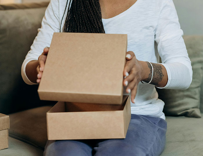 Person opening a cardboard gift box, potentially having bad luck with Secret Santa.