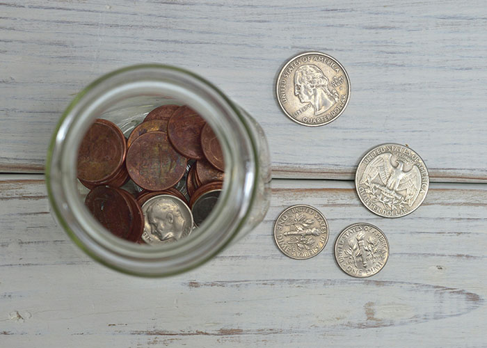 Jar of coins on a wooden table, representing financial difficulties during Christmas.