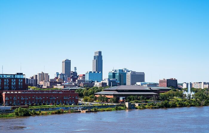 Skyline view of a city by the river on a sunny day, with multiple high-rise buildings visible.